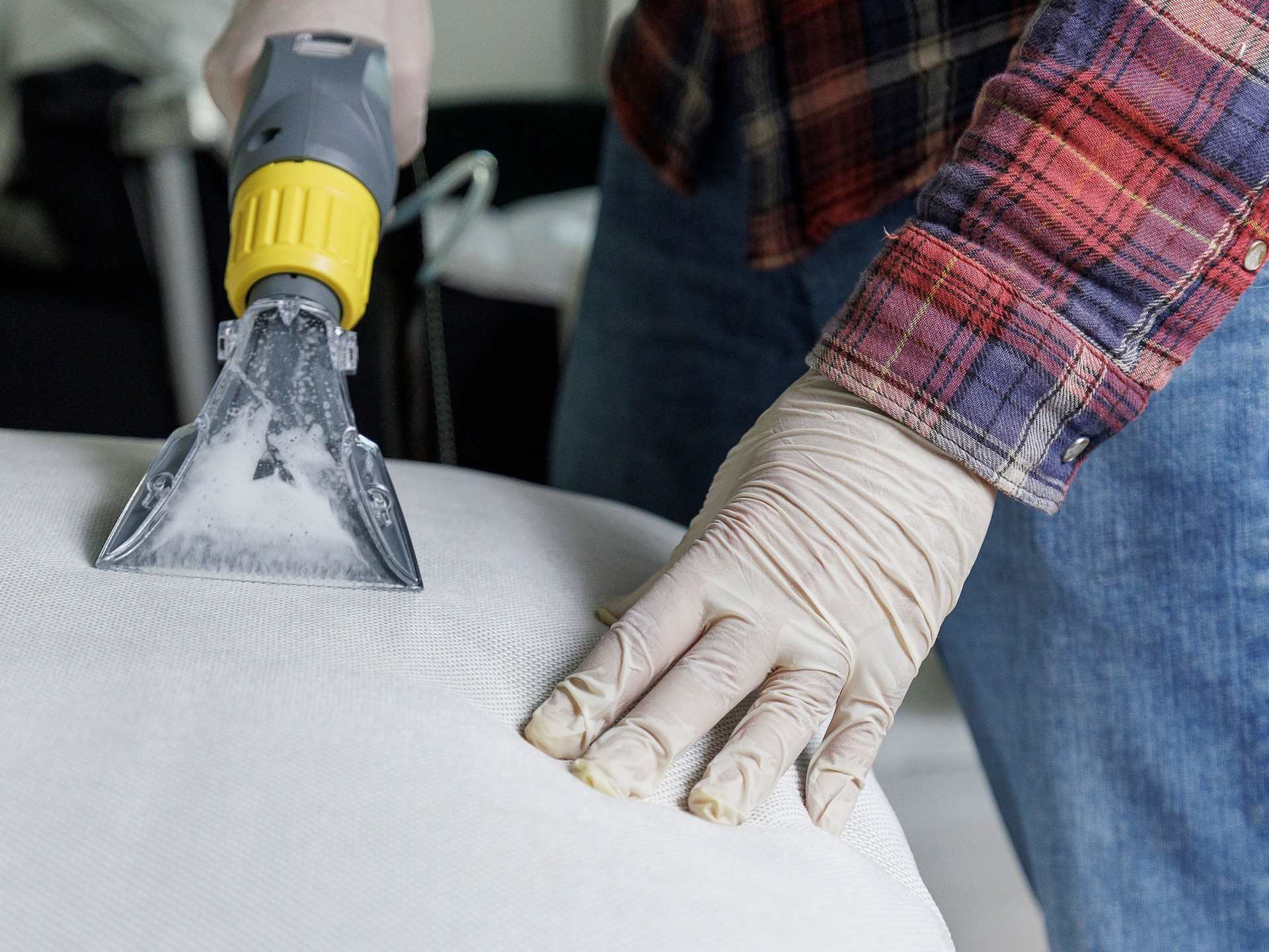 Dirty water bubbling in the nozzle of washing vacuum. Worker using professional vacuum-cleaner for deep washing.